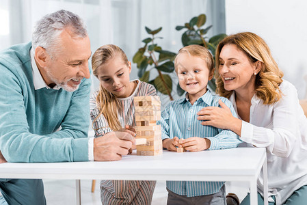 微笑的祖父母和孙辈在家里一起玩木塔游戏图片
