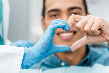 以牙科医生和非美裔病人的手做心脏形状有图片