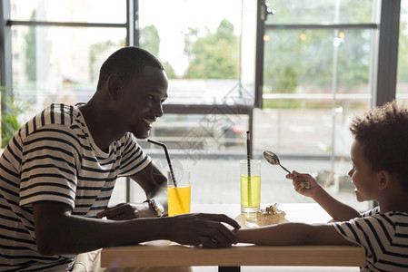 在咖啡馆喝柠檬水的非洲父亲和儿图片