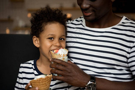 在咖啡馆用冰淇淋喂着可爱的小儿子喝着冰淇淋的图片