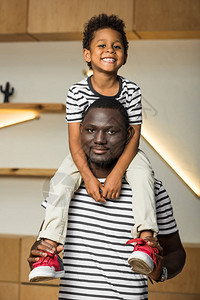 快乐的非洲裔美国父亲脖子上挂着可爱的小儿子图片