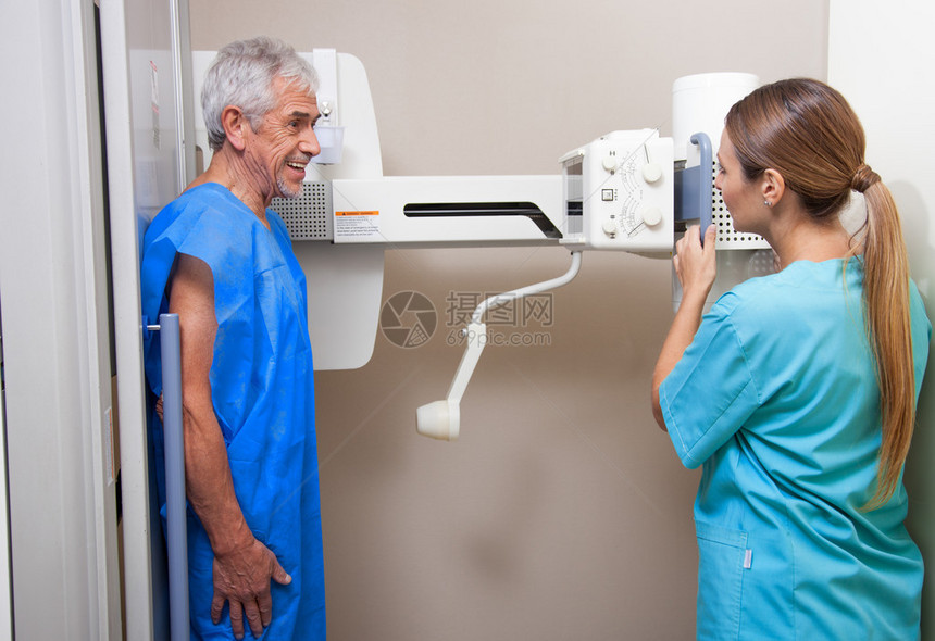 60多岁的男病人在微笑美丽的女医生的协助下接受了X光检查医院的现场图片
