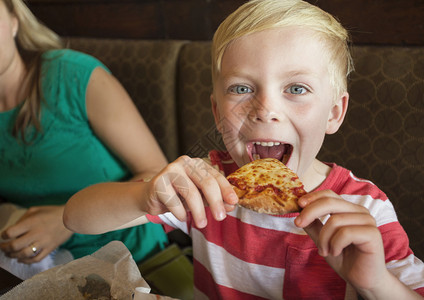 小可爱男孩在餐厅吃大口奶酪比萨饼吃了一图片