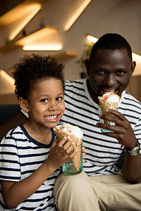 快乐的非洲美国父亲和儿子吃冰淇淋在图片