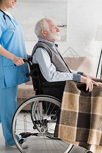 护士带有轮椅残疾和灰色头发男子的割图片