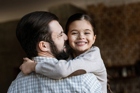 快乐的父亲和女儿抱在家里看摄图片