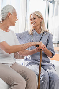 护士和快乐的年长女人用拐杖在养老背景图片