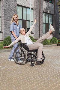 带着坐在轮椅上快乐的老年病人的笑图片