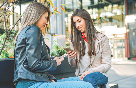 站在城市地区的年轻女在城市户外与移动智能手机连接图片