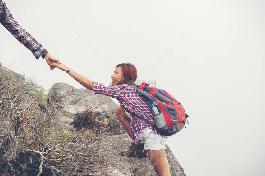 年轻的时髦男人帮助女人爬山图片