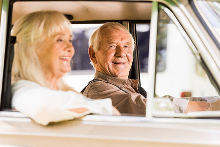 老爷车里微笑的老人和女人的侧视图图片