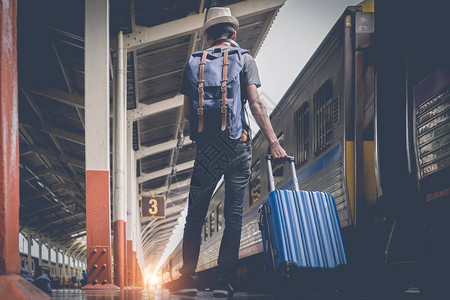 年轻旅行者带着手提箱和经典列车在铁路平台上行走单是旅行概念图片