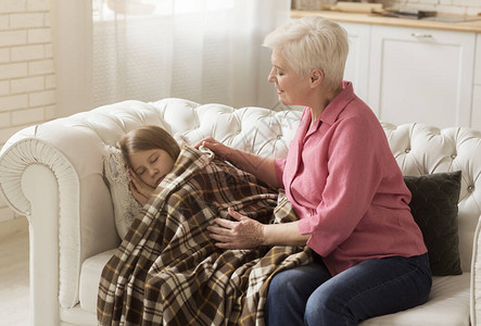 幸福的外婆在家睡觉时用温暖的格子罩着孙女图片