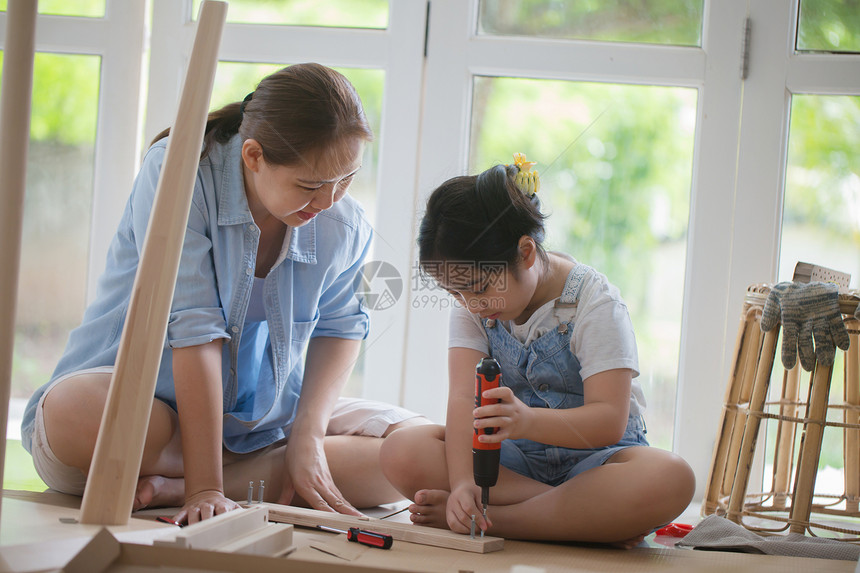 亚洲可爱的小女孩帮妈在家里装新DIY家具图片