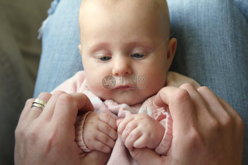 一个漂亮的3个月大的女婴坐在她父亲的腿上图片