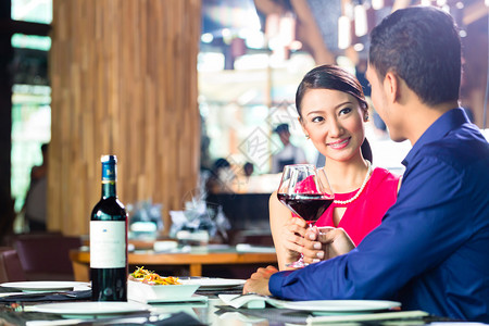 亚洲情侣在非常豪华的餐厅里共进晚餐和喝红酒图片
