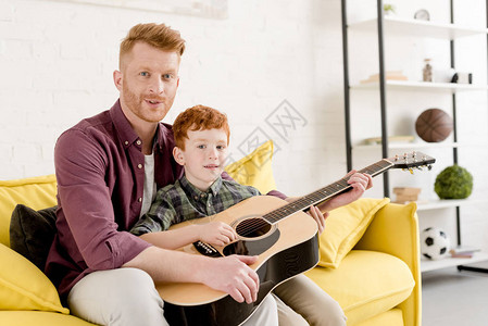 快乐的父亲和儿子拿着音响吉他在家里对图片