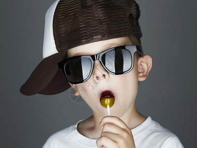 有趣的小男孩在吃棒糖时装小孩戴太阳图片