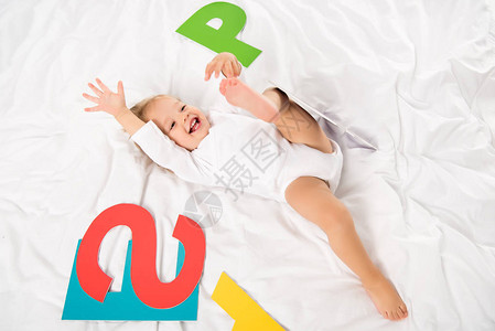 快乐婴儿的俯视图纸质字母躺在床上图片