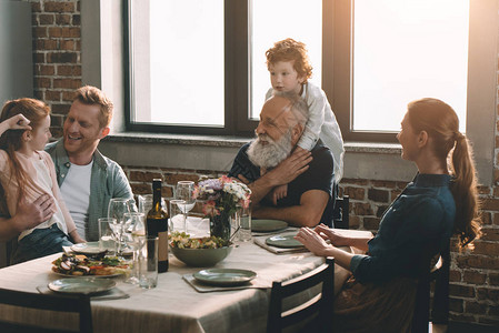 在家里的家庭聚餐中拥抱祖父的小男孩图片