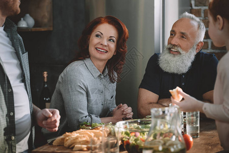 喜悦的老年夫妇和家里人在家里厨房里吃图片