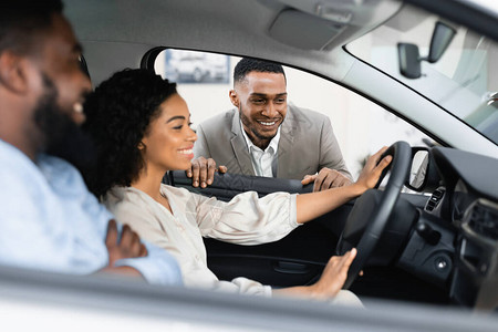汽车销售黑人夫妇选择新车与坐在汽车经销店的经销商交谈图片