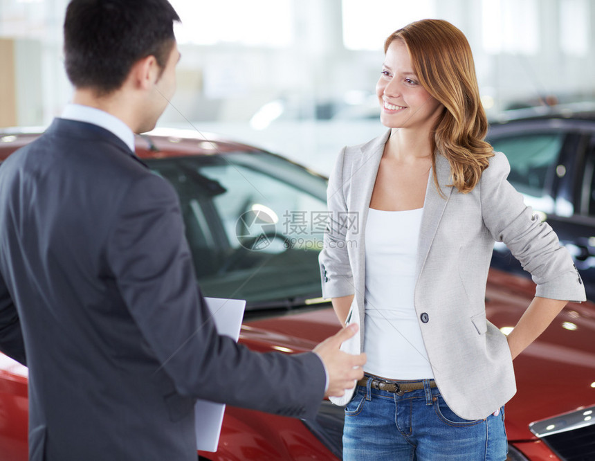 成功的年轻女士与汽车经销商讨论她可能购图片