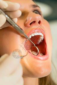 身戴手套的有牙科治疗牙医的女病人图片