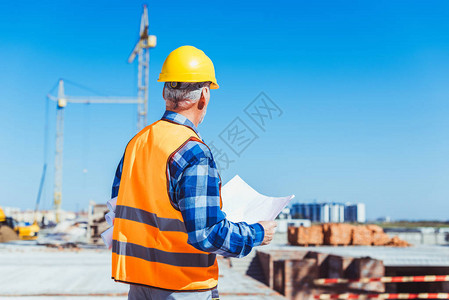 身着反光背心和安全帽的建筑工人站在建筑工地背景图片