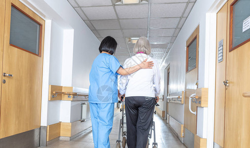 亚洲医生在医院走廊里帮助年纪较大背景图片