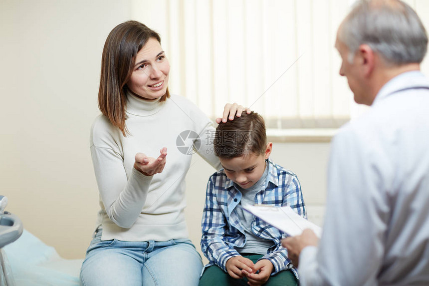 在医院看病期间与儿子医生交谈的年轻女子图片