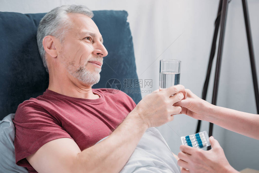 妇女向生病的丈夫提供药品和水杯图片