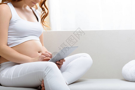 孕妇在家中坐在沙发上时使用数字片图片