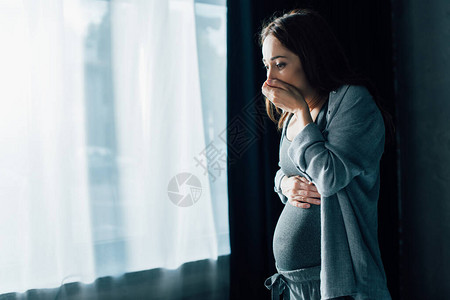 黑发孕妇在家中站着时嘴唇遮住嘴巴图片