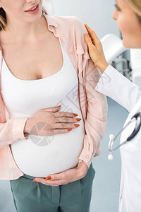 孕妇触摸肚子和在妇科诊所与医生咨询时的作物切入眼图片