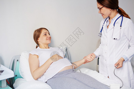 年轻孕妇躺在床上而医生测量她的压图片