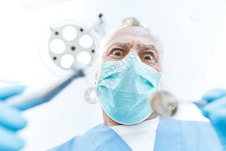 戴着医用口罩的兴奋的专业牙医拿着牙科工图片