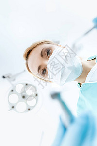 戴医用口罩的专业牙医在诊所工图片