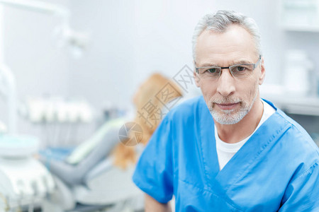 高级牙医在牙科诊所与病人后面的牙科图片