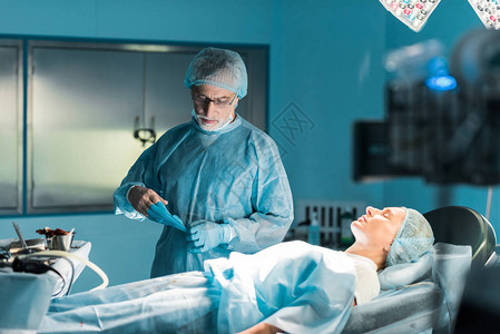 医生在手术室病人附近摘下医疗图片