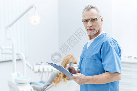 高级牙医在牙科诊所剪贴板上统一写字病图片