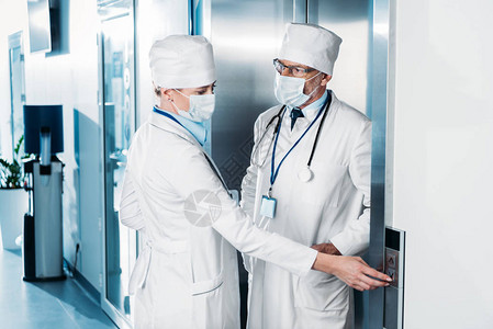 戴医用口罩的女医生按下电梯按钮并在医院走廊图片