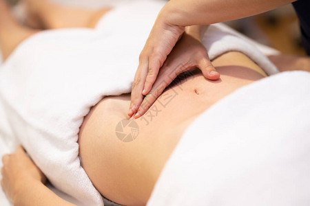 在理疗中心接受腹部按摩的妇女患者正在接受专业整骨背景图片