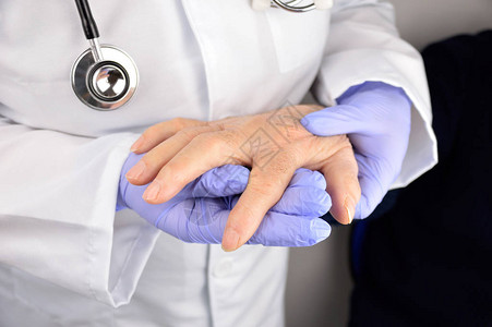 女医生帮助老年男病人将手握在手指上图片
