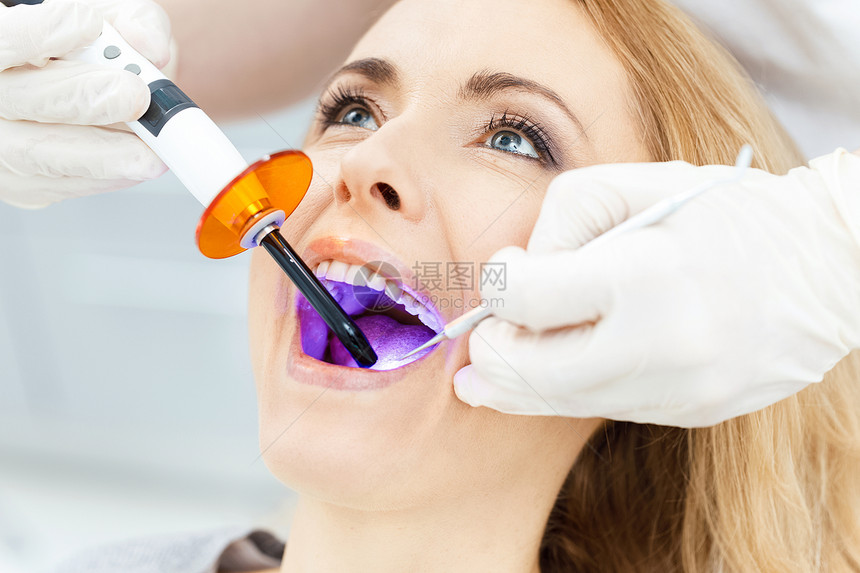 在病人牙齿上使用牙科修补紫外线灯的牙科图片