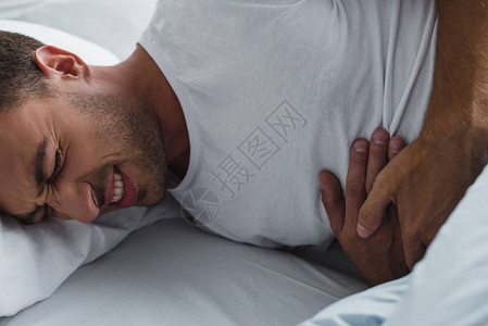 床上腹部疼痛的男子图片