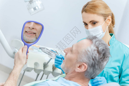 成年患者在专业牙医检查牙齿时照镜子图片
