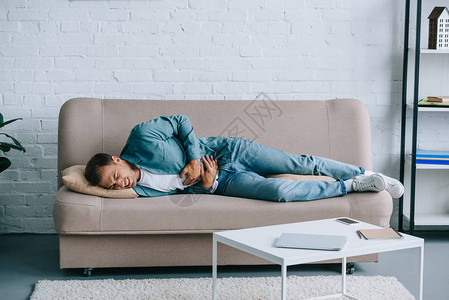 年轻人躺在沙发上在家肚子疼图片