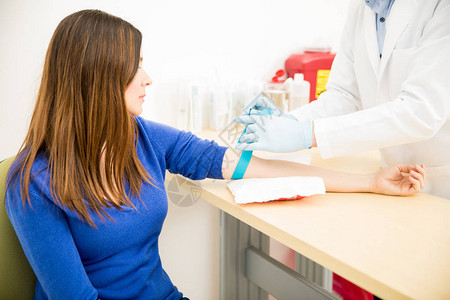 一名男医生在实验室抽血前将橡皮筋绑在病人图片