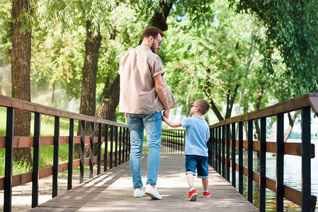 父亲和儿子手牵在公园桥背景图片